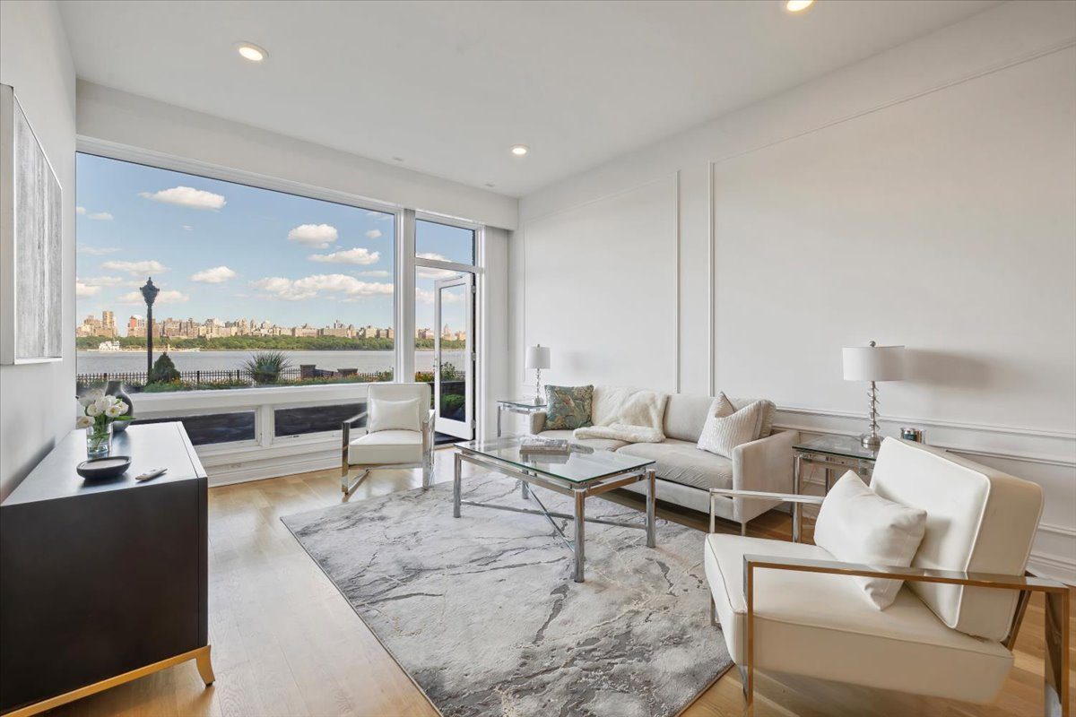 Living room at 9 Somerset Lane, Unit 118, with floor-to-ceiling windows facing the Hudson